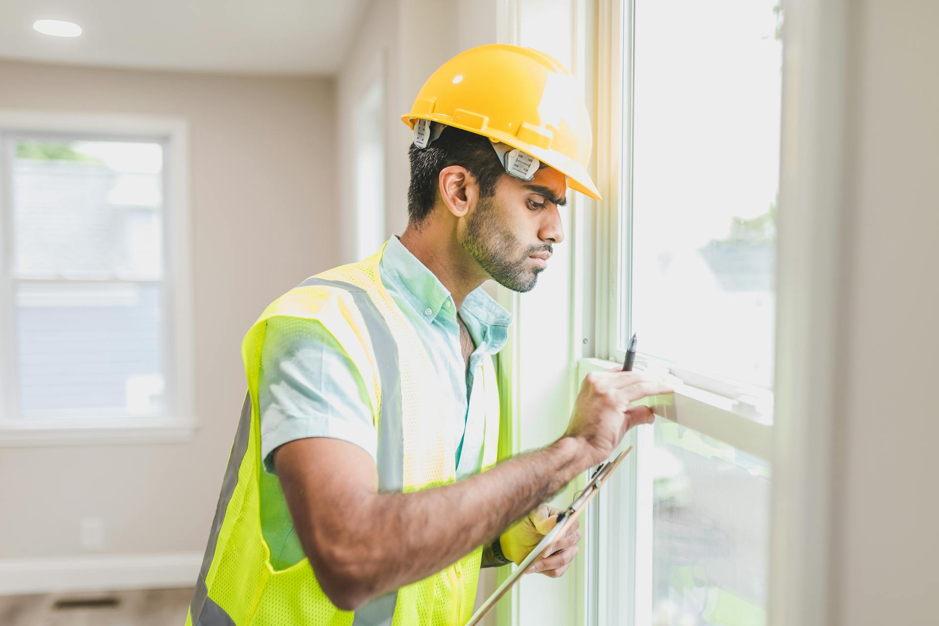 construction-worker-in-yellow-safety-vest-and-helmet-checking-glass-window-of-a-house construction-worker-in-yellow-safety-vest-and-helmet-checking-glass-window-of-a-house